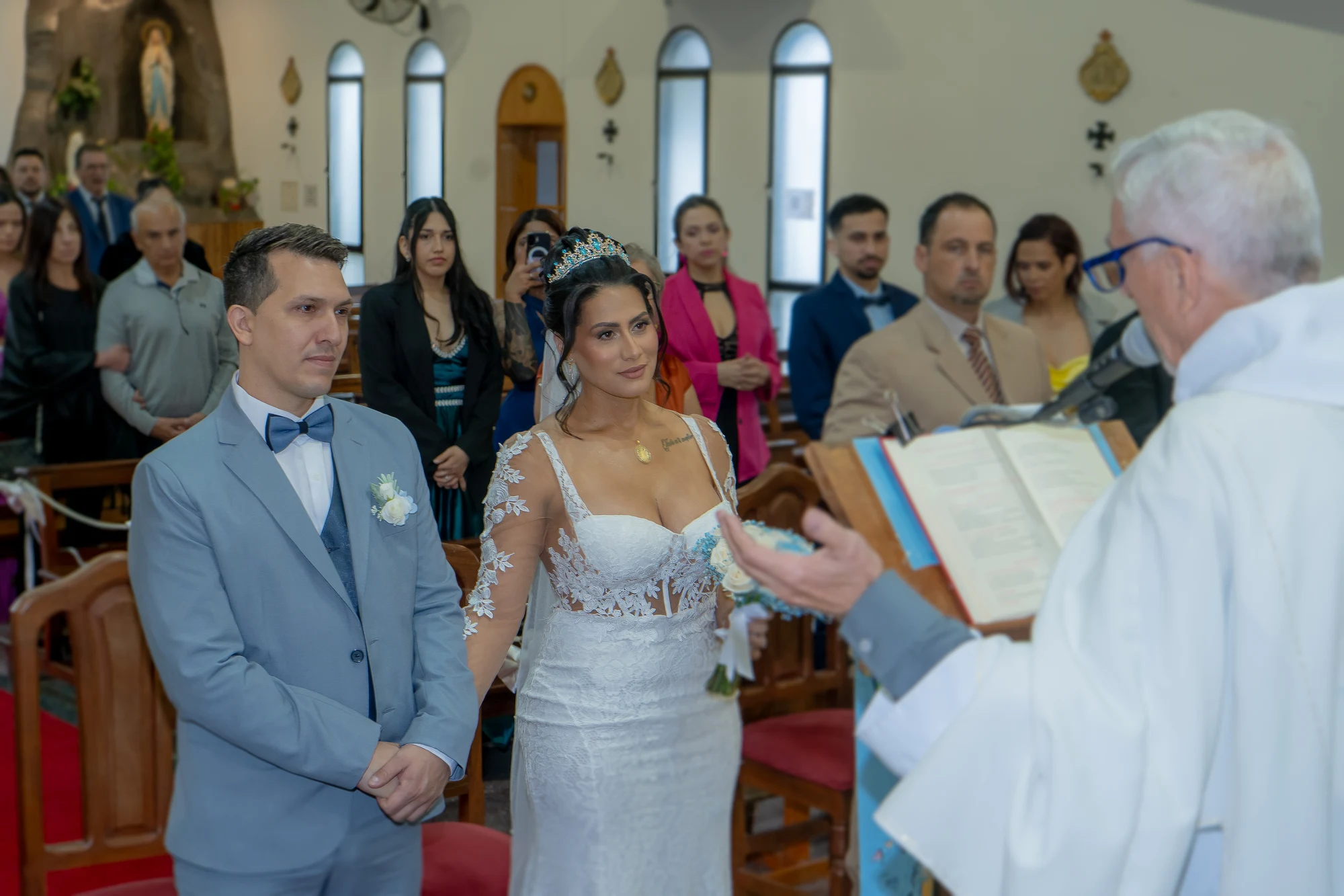 La pareja escucha al sacerdote, acompañada por sus invitados.
